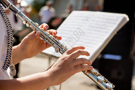 女孩吹长笛音乐会期间女孩手中的长笛在古典音乐会上演奏长笛图片