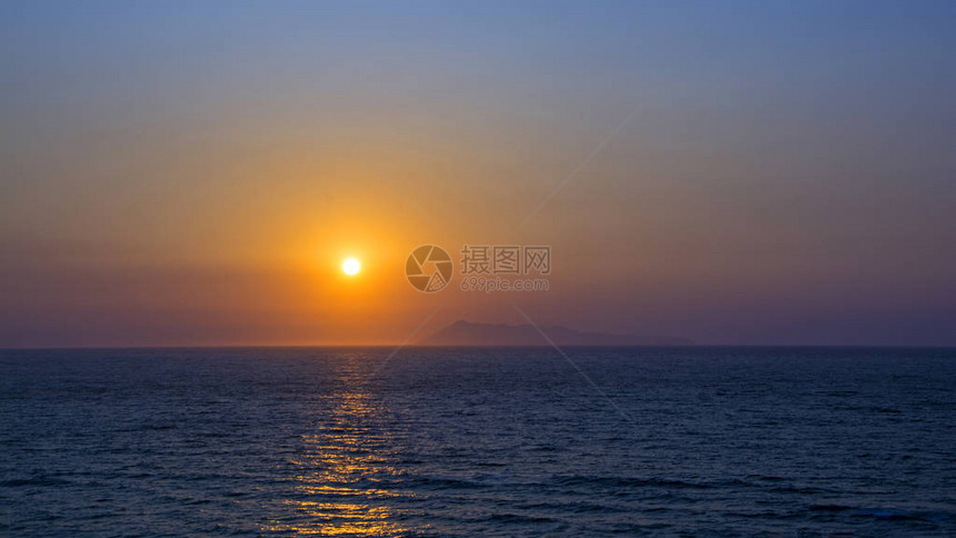 太阳在海上或海洋的日落出时落在地平线上宁静的海浪自然的天蓝色和橙色全图片