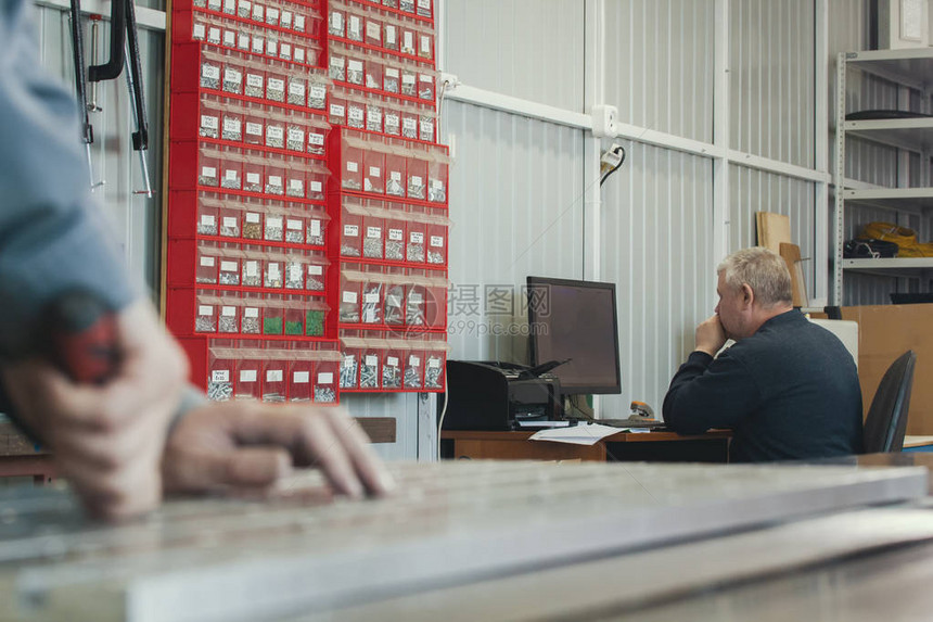 工人手在生产厂的计算机中工作的成年男子面前切割金属细节图片