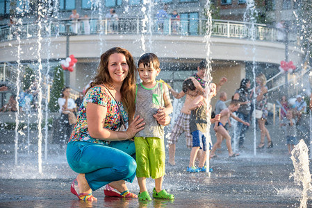 快乐的孩子们在炎热的夏日在城市喷泉玩耍父母与他们的孩子积极的家庭休图片