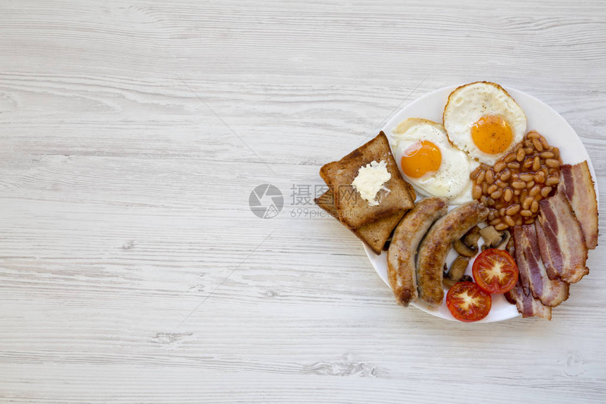 英式早餐用煎鸡蛋香肠豆类培根和烤面包在白色木制背景顶视图平躺从上面图片