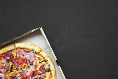 黑色背景的纸板盒里新鲜烤披萨图片