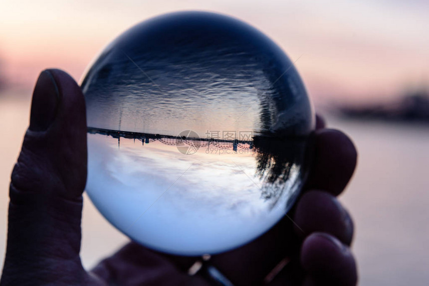 日落时水晶球中的桥和反射手握图片