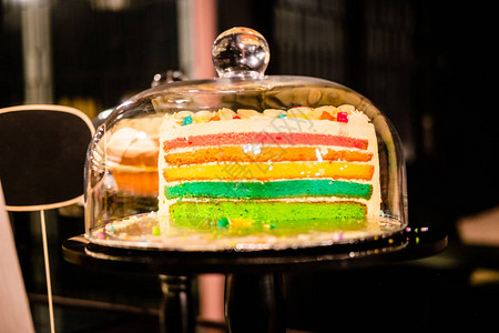 彩虹层蛋糕在玻璃铃穹顶下蛋糕摊甜点储图片