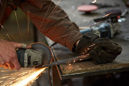 铁匠手在铁匠铺的锻造上方操作金属件的特写镜头图片