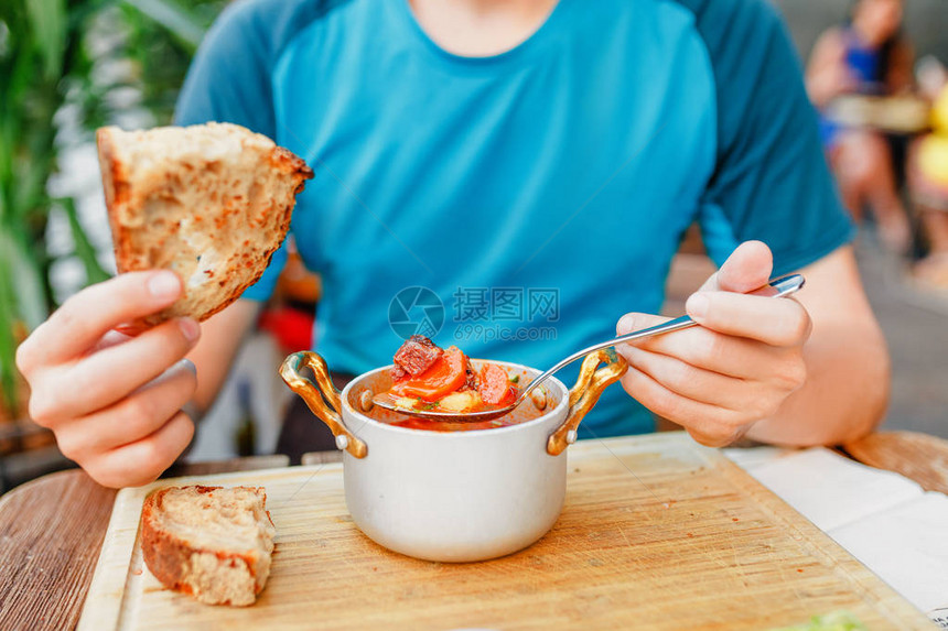 男人在户外餐厅吃传统的匈牙利口香糖或番茄汤时用图片