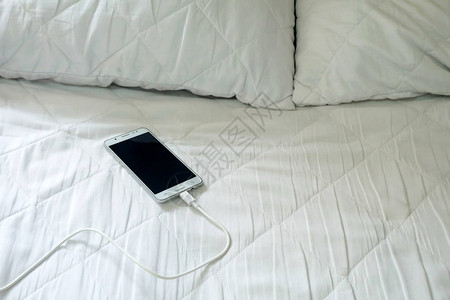 智能手机在白床上充电图片