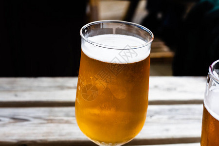 杯啤酒在木桌上酒吧供应生啤酒杯在木板上的淡啤酒背景模糊的酒精饮料在玻璃杯中背景图片