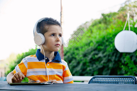 男孩在外面戴着耳机听音乐背景图片