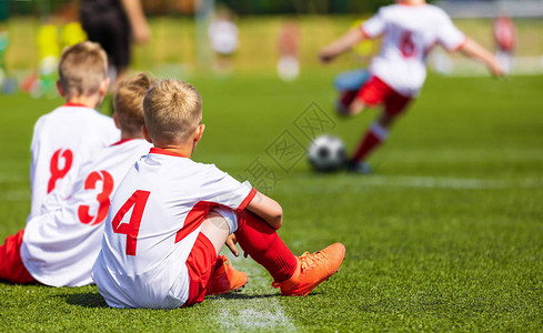 年轻男孩在球场上踢足球比赛图片