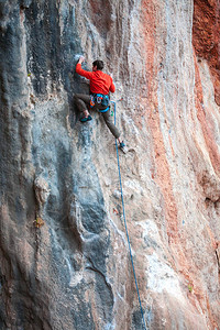 一个人爬上岩石在大自然中攀爬户外健身积极的生活方式极限运动运动员在自图片