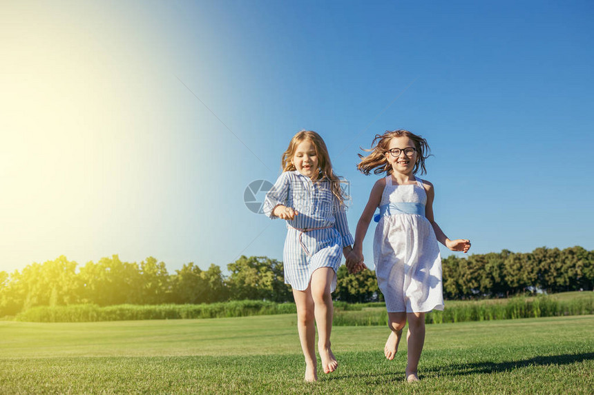 两个女孩在田里跑来去穿蓝裙子的姐妹图片