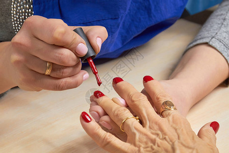 美甲师用红清漆把指甲涂在女人身上图片