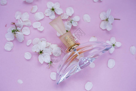 粉红色背景中带有白色花瓣的香水图片