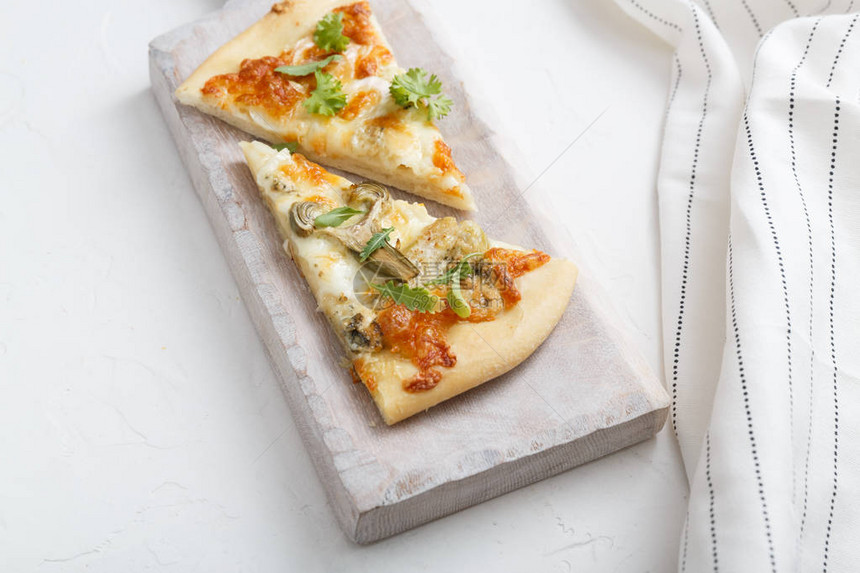 白色切菜板上的两块奶酪披萨图片