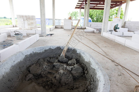 建筑施工墙在桶中混合水泥石膏混凝土背景图片