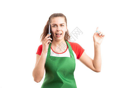 年轻女超市或大卖场员工使用智能手机打电话并用食指点在白图片