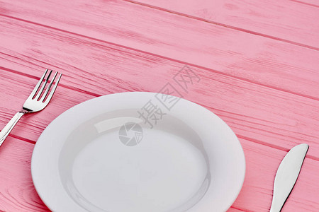 空盘子叉子和刀子放在木头上粉红色的木桌设置与白盘和不锈钢叉图片
