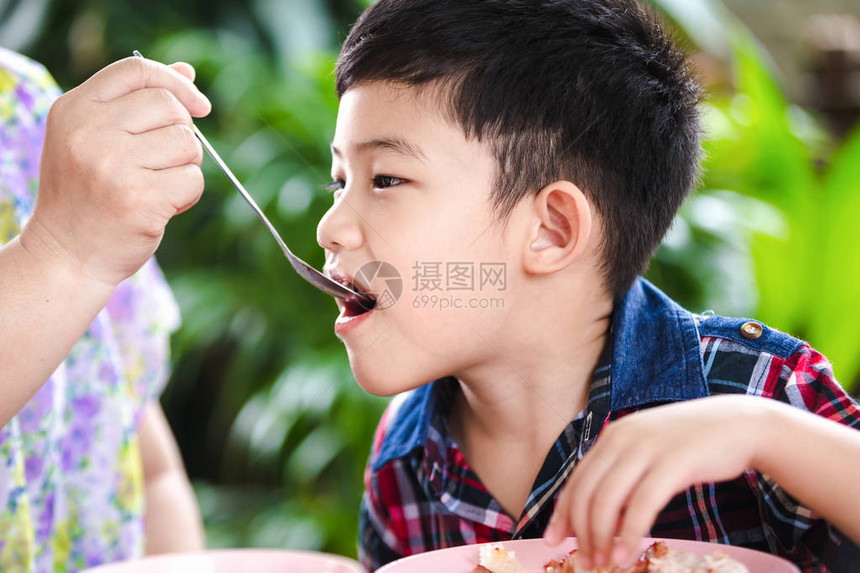 亚洲小男孩在木桌上吃大米饭图片
