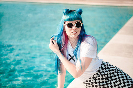 蓝头发的年轻女子身着太阳墨镜在游泳池上图片