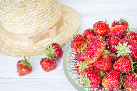 白色木质背景中的草莓和草帽图片