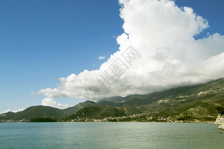 阳光明媚的地平线上山峦云雾的海景照片图片