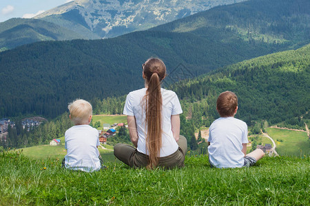 家庭节日母亲和两个儿子欣赏山的景象背图片