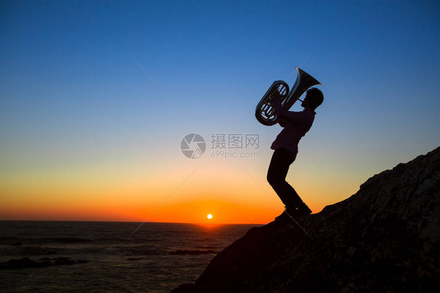 音乐剧Tuba的轮廓在令人惊叹的夕阳下图片