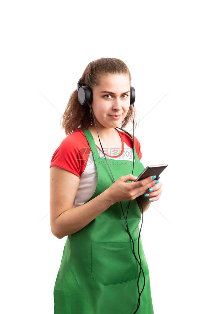 年轻女零售或超市女工在电话和耳听器上收听音乐图片