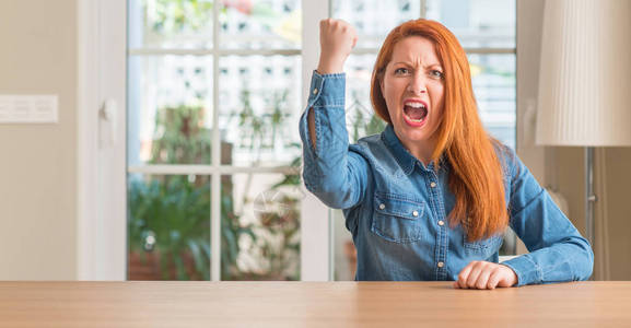 在家的红发女人愤怒而疯狂地举起拳头沮丧和愤怒图片