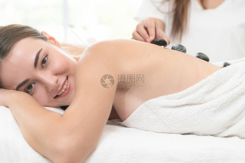 女人在spa沙龙接受专业美容师治疗师的热石按摩治疗豪华健康缓解背部压力和恢图片