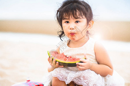 夏天在热带沙滩上吃西瓜的可爱孩子图片
