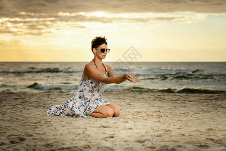 穿着裙子的美女在沙滩上坐着在图片