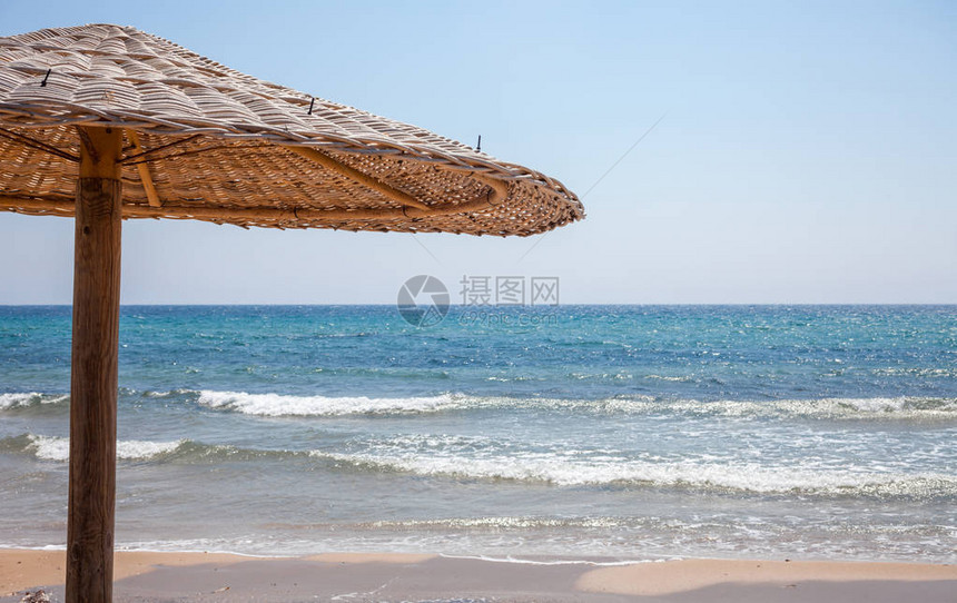 高大的伞站在沙子里一个木制的Bonita小屋为海岸线提供遮荫灿烂的太阳照耀在海面上放松的旅游目的地图片