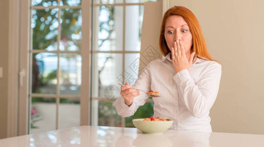 红发女人在家中吃麦子时用草莓遮住嘴唇图片