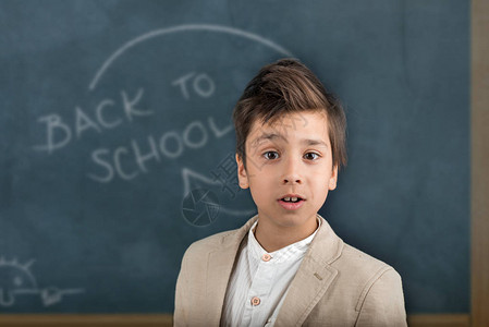 男生站在学校的黑板上微笑在板上题字粉笔图片