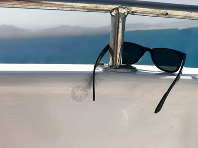 黑色塑胶太阳镜挂在一艘游艇上的铁栏杆上图片