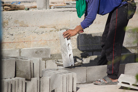 水泥块泥工或砖建造者在建筑工地建造水泥砖墙工人们正在建造筑物背景