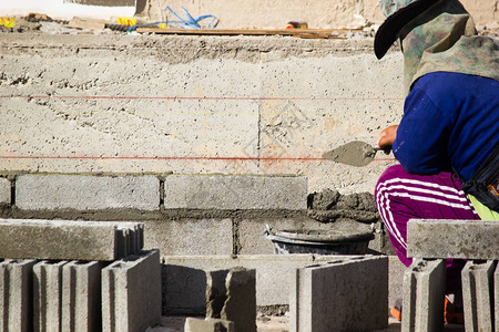 泥工或砖建造者在建筑工地建造水泥砖墙工人们正在建造筑物背景