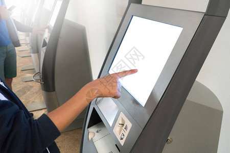 亚洲男孩通过在国际机场终端使用kiosk自我报到机背景图片