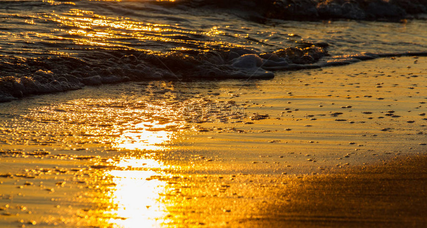 在沙滩和日落时的太阳反射中破浪所创造的美图片