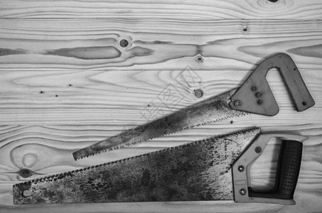 黑白木桌上的一把旧钢锯图片