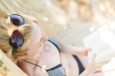 在海边的吊床里看书的女图片