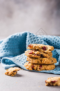 以浅灰色背景和蓝餐巾纸的葡萄干和红莓为食用烤面包饼干图片