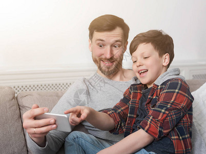 有趣的父亲和儿子在家玩得开心用智能手图片