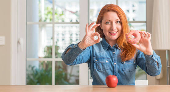 红发女人在苹果和甜圈之间做出选择用手指做好标记图片