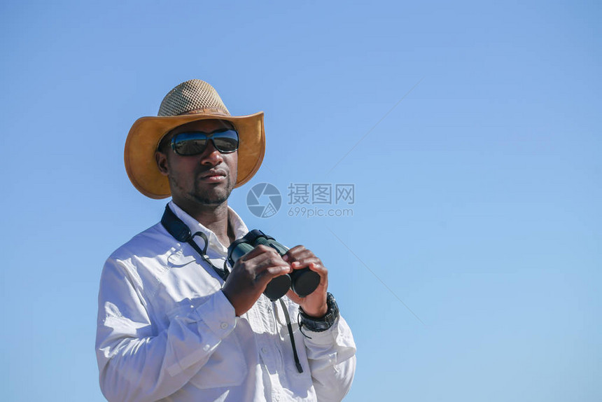 身着帽子和白衬衫的非洲男子站在游猎车旁图片