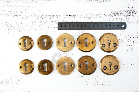 旧的铜门锁覆盖着破旧的白色木质背景图片