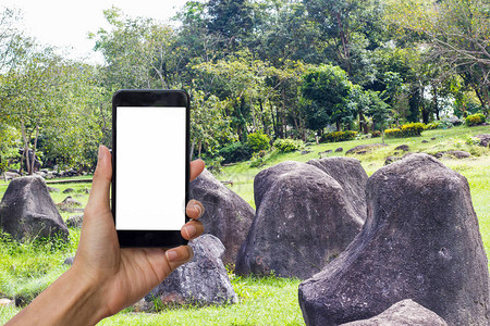 手持黑色智能手机和白色屏幕在石园上作为图片