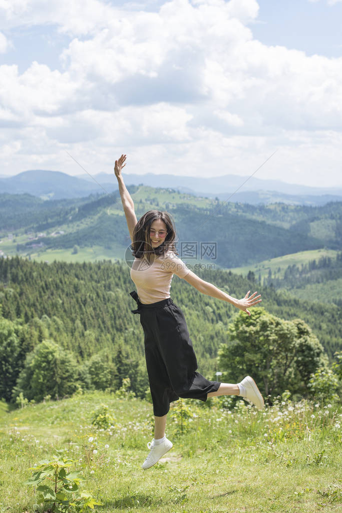 可爱的女孩在山林的边缘跳跃着阳光夏图片